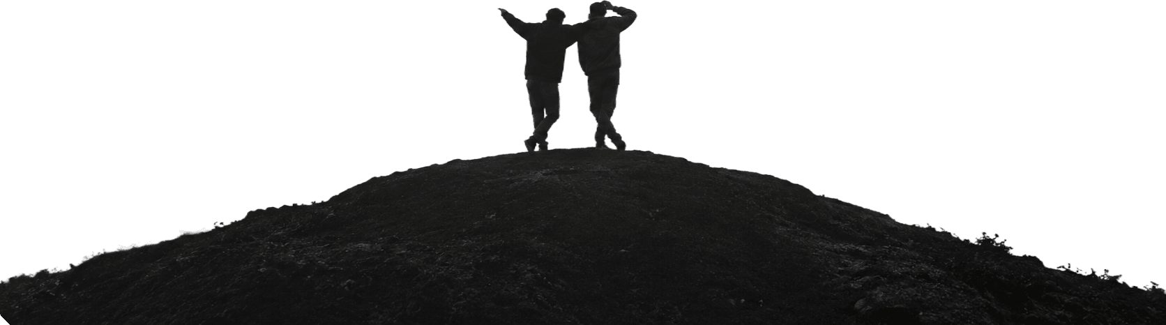 Dos personas abrazadas en lo alto de un monte, de espaldas, mirando al horizonte